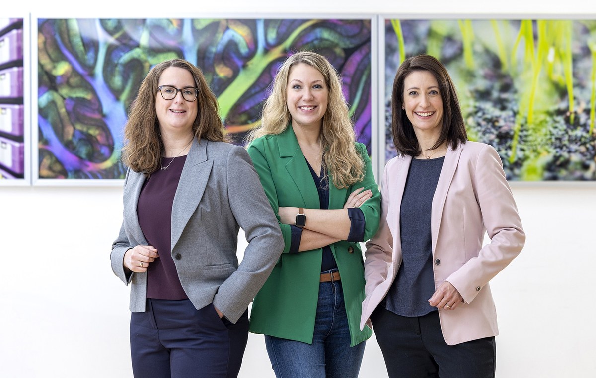 Dr. Sabrina Röttger-Wirtz, Dr. Stefanie Vus und Dr. Jennifer Pahlke stehen nebeneinander und lächeln in die Kamera. Im Hintergrund hängen bunte Bilder an einer Wand.